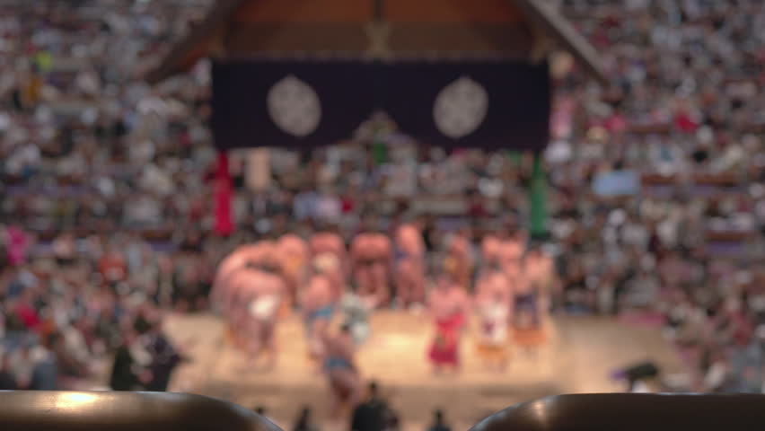 Sumo wrestlers stand on the flatform for the opening ceremony before matches begin. Defocused shot.