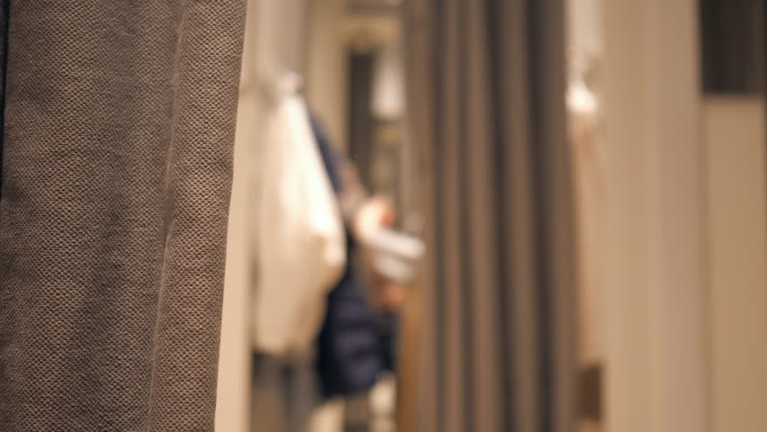 Slow motion of girl changes clothes in a fitting room, defocused. 