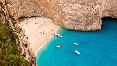 Animated cinemagraph photo of Navagio shipwreck beach with boats and tourists in Zakynthos, Greece. Loopable motion background animation with moving waves.