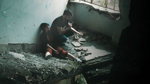 two guys (man and woman) taking drugs in an abandoned building