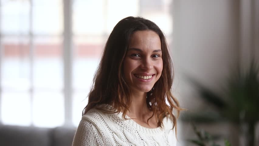Video portrait of happy attractive casual young woman with beautiful face posing at home, positive pretty millennial or teen girl looking at camera indoors, female student smiling wide feeling good 
 | Shutterstock HD Video #1022264140