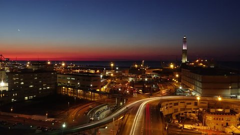 Lighthouse and city interchange traffic in seaport area of Genoa, Italy. Night to day time lapse