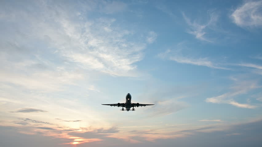 4K Overhead flying aircraft landing at sunset or sunrise