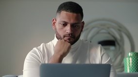 Pensive tired businessman thinking over business solution. Man looking through webpage on laptop monitor carefully, touching face and thinking. Problem solving concept