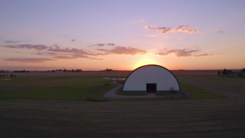 Sun setting over country side behind barn
