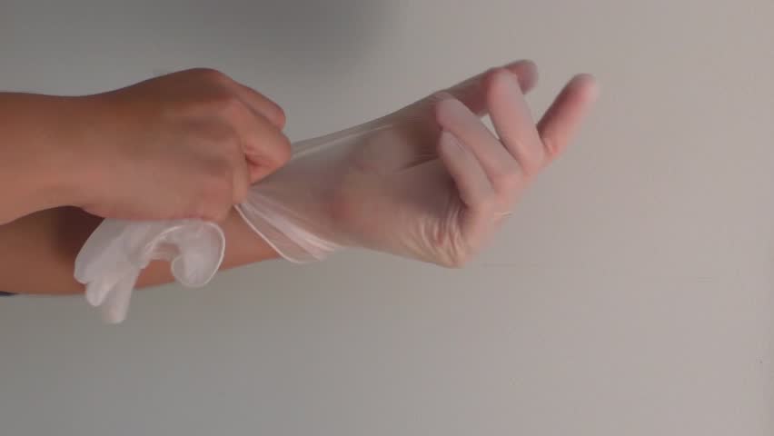 Female putting clear plastic glove on left hand. | Shutterstock HD Video #1022276617