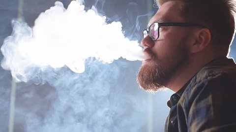 Attractive man exhaling smoke from the nose. Man in glasses advertising a hookah. Slow motion