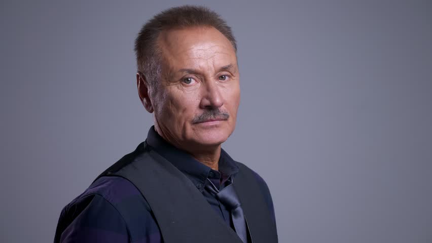 Closeup portrait of senior caucasian man lookin straight at camera calmly turned to the side