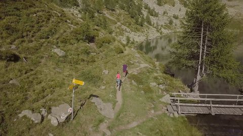 Drone view of young couple trail running in the mountains. Aerial view of trail runners exercising near stunning Alpine lake in Switzerland 