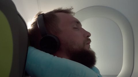 A man sits by the window in the plane and sleeps