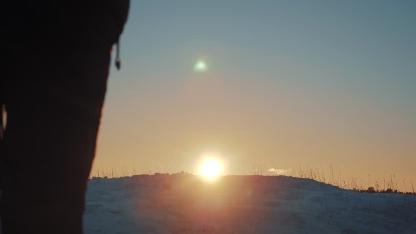 victory business travel concept. man traveler hiking in winter mountains. trekking in wintertime cold snowy weather. rock man climber silhouette over natural lifestyle colorful sky with bright sunset