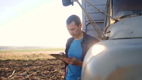 smart farming. man farmer driver stands with a digital tablet near the truck. slow motion video. Portrait lifestyle businessman farmer standing in the field harvesting season car. Farmer driver uses a