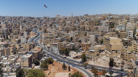Panorama timelapse of the city of Amman, Jordan with flag view from Jabal Al Qal'a, the Citadel of Amman. Urban Sprawl 4K footage