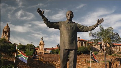 Pretoria, South Africa - circa January 2019: Statue of Nelson Mandela in the gardens of Union Buildings, government offices in capital city, with South African flag flying in wind on sunny day, jib up