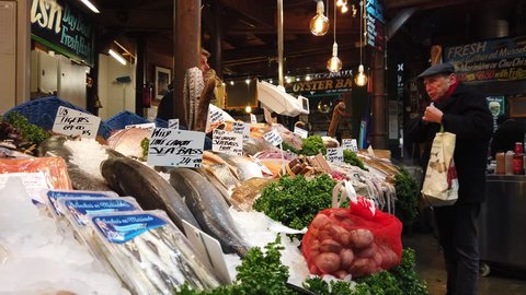 BOROUGH MARKET, LONDON - JANUARY 10, 2019: A customer purchases seafood from a fishmonger at Borough Market in Southwark, London, UK.