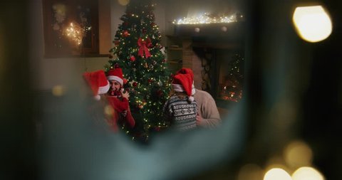 Slow motion of happy family having fun to celebrate Christmas holidays, opening presents view from snowy window. Shot with RED camera in 8K. Concept of Christmas time, winter holidays,family tradition