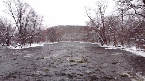 Drone view of Winter wonderland with snow falling, raging river rapids.
