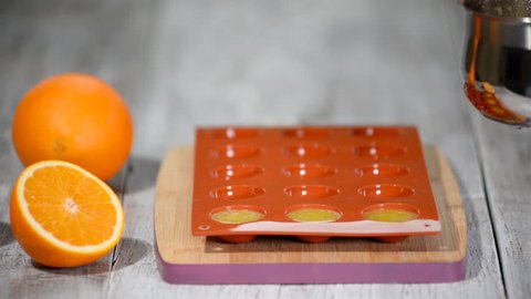 Pouring orange jelly in the silicone mold.