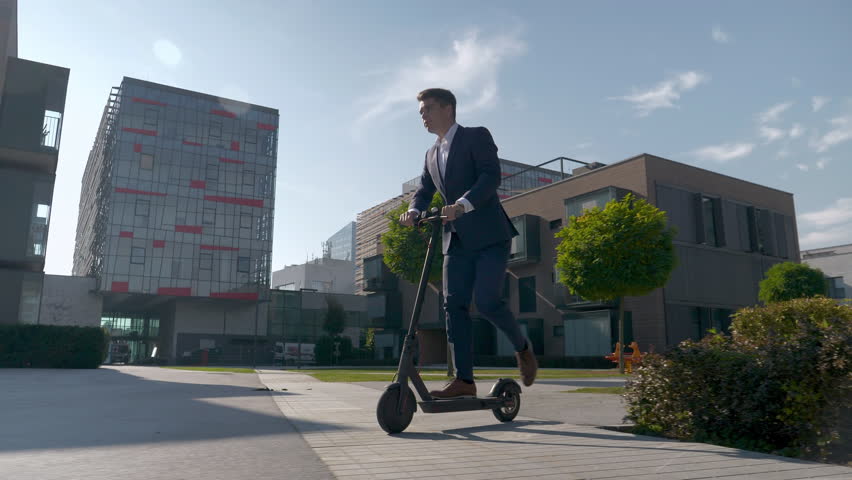 Slow motion - Adult businessman riding with electric scooter to work Royalty-Free Stock Footage #1022356144