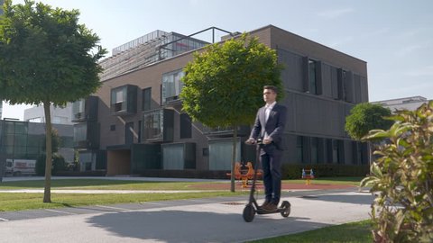 Slow motion - Man in a suit riding electric scooter