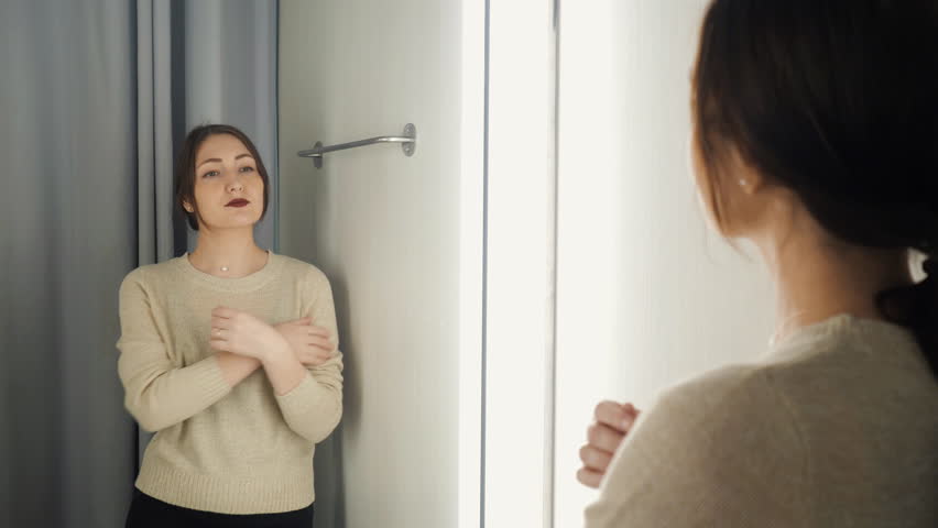 The girl measures the clothes in a fitting room.