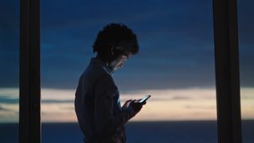 young man using smartphone in hotel room texting sharing vacation lifestyle on social media enjoying view of ocean at sunset - Powered by Shutterstock - Get 15% off with code: PIKWIZARD15