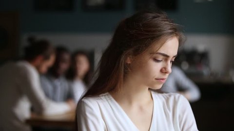 Upset offended millennial girl student alone in cafe feeling lonely excluded ignoring friends after conflict, sad young woman introvert loser avoiding people being rejected by students community