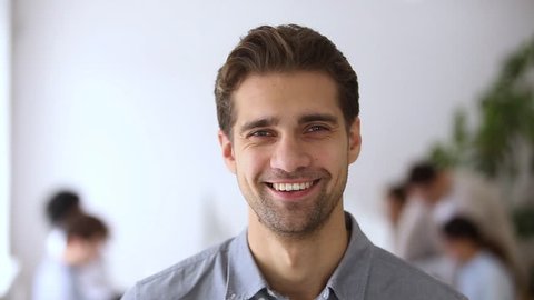 Young male team leader with smiling face posing in office, confident business executive ceo looking at camera, company employee, professional manager businessman, startup founder video portrait
