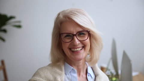 Happy mature middle aged businesswoman executive wearing glasses with smiling face looking at camera, senior older attractive woman female professional teacher coach professor video portrait
