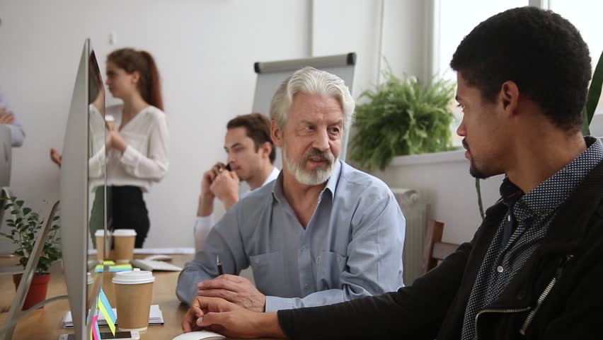 Older male mentor helping teaching new employee explaining intern giving instructions in office, senior corporate leader teacher executive training young worker listening learning new skills at work | Shutterstock HD Video #1022373430