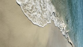 Vertical video. Sea wave on the sandy beach at summer vacation