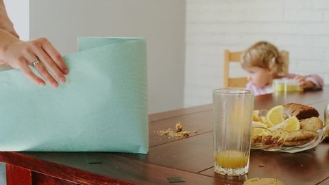 Mother Tears Off A Paper Towel. Mom Wipes The Crumbs Off The Table With A Paper Napkin.