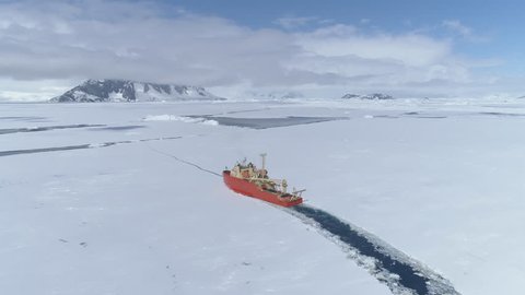 Antarctica Icebreaker Boat Break Ice Aerial Zoom in View. Laurence M. Gould Research Boat Float Through Thin Southern Ocean Frozen Surface at Packice Top Flight Drone Shot Footage 4K (UHD)