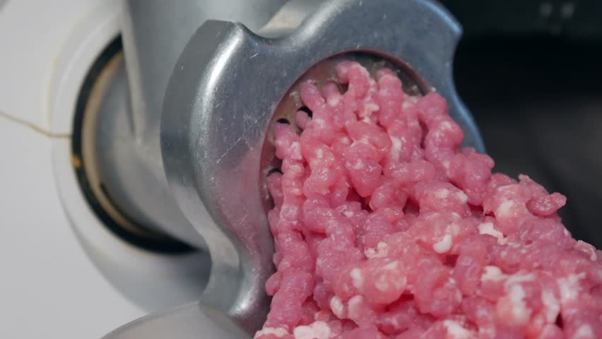 A man twists pork meat in an electric meat grinder | Shutterstock HD Video #1022394589