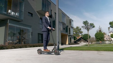 Slow motion - Businessman riding electric scooter to work