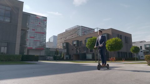 Slow motion - Young man in a suit riding electric scooter
