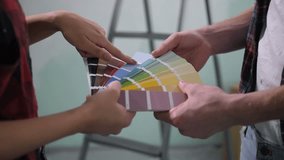 Close-up of couple hands choosing color for painting interior wall from color smaples palette during home renovation. Multi ethnic diy family making decision together about color of house interior. - Powered by Shutterstock - Get 15% off with code: PIKWIZARD15