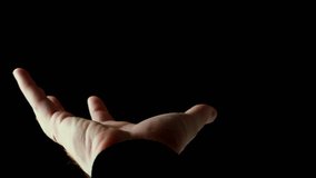 Human male palm in the rays of light isolated on black background. A man shows an open hand, then slowly clench his fingers into a fist. Stock video slow motion