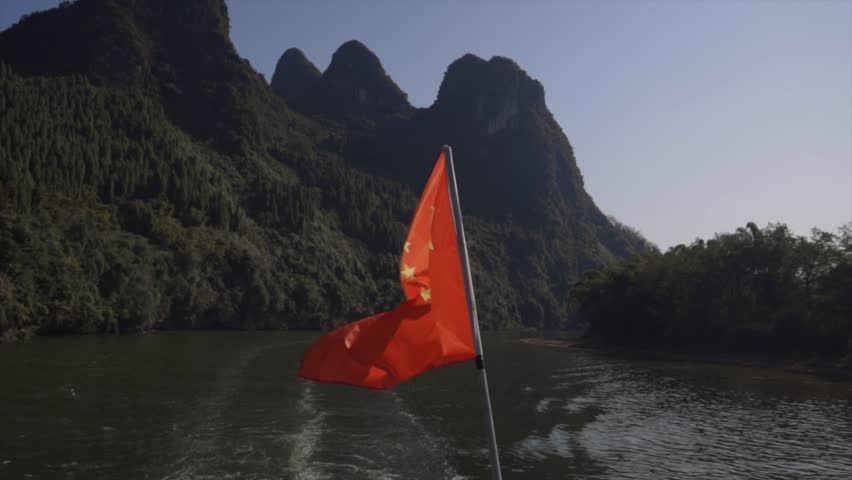 Chinese flag on boat with a beautiful view of mountains from Guilin, Mainland China on the Li River.