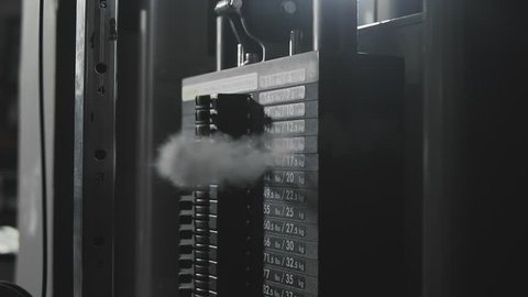 Weight falling in block machine and cloud of powder raising in dark gym in slo-mo.