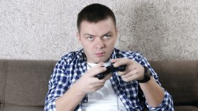 Young man playing video games at home. guy sitting on couch with joystick in hands
