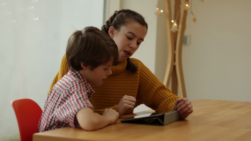 Sister And Younger Brother Using Tablet Together At Wooded Dinning Table | Shutterstock HD Video #1022417077