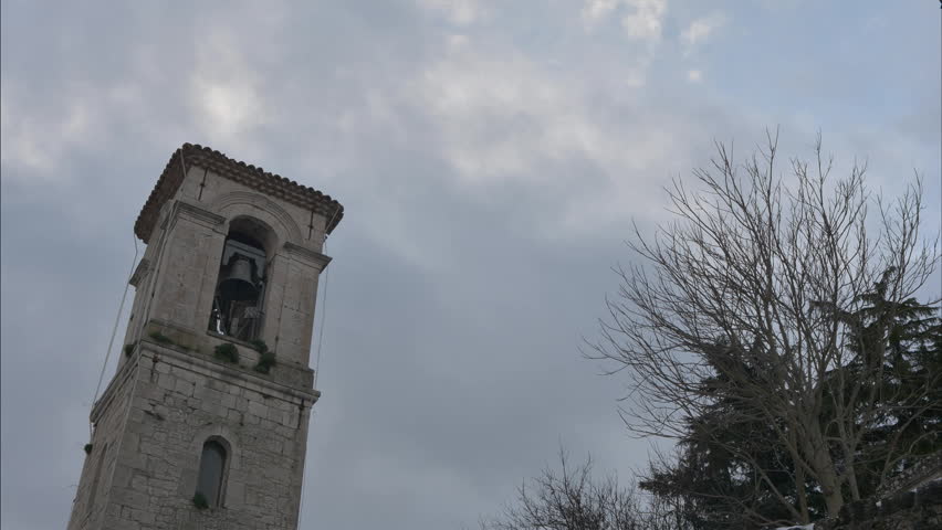 Ancient church in central Italy, view of the belfry in time lapse with clouds