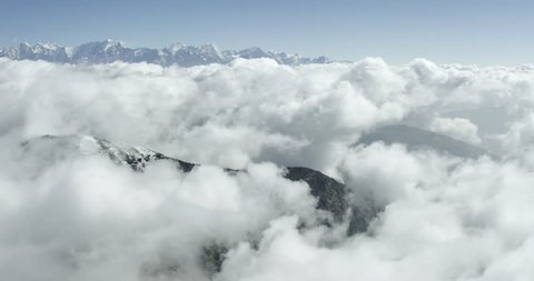 Epic clouds covering himalayan mountains in a wide shot POV aerial over a cold rocky mountain range near Mount Everest Nepal in Tibet