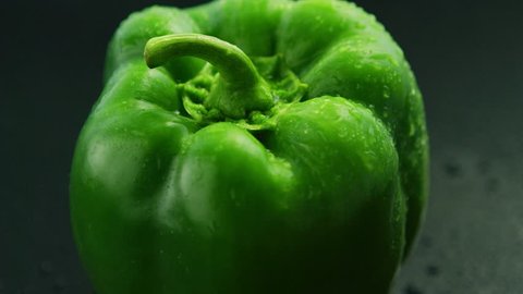 Closeup of shiny green bell pepper with drops of water shining on glass wet surface