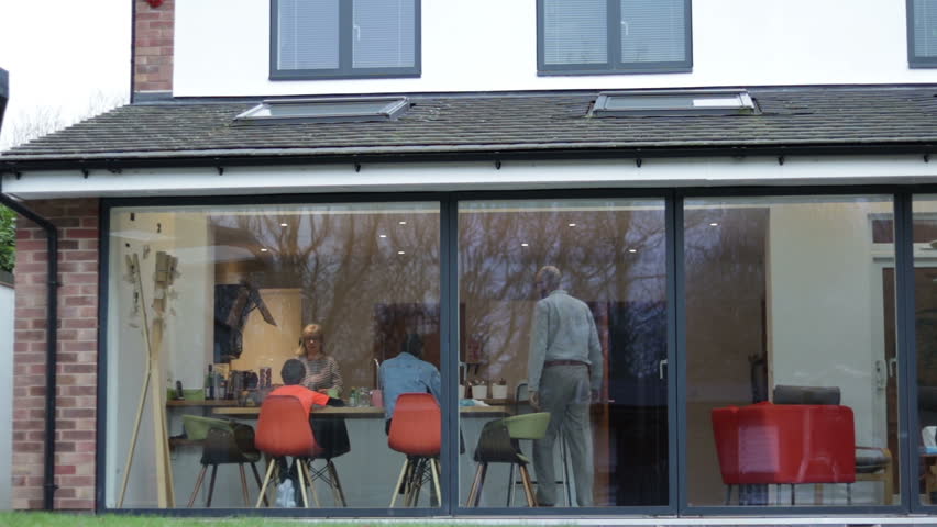 Authentic Modern English Family Having Lunch Together In Kitchen Dinner Viewed From Outside Glass Doors