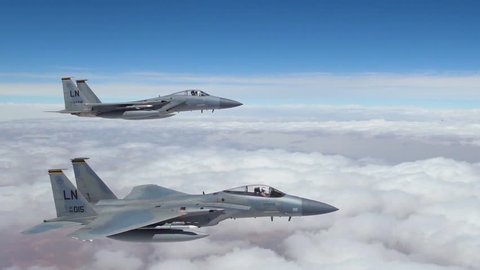 CIRCA 2018 - American F-15 fighter jets fly in formation high above the clouds and then peel off.