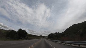HD video driving POV on Highway 46 between PCH and the 101 freeway. White clouds on a sunny day iconic central valley drive through California, hillsides green from recent rain fall.