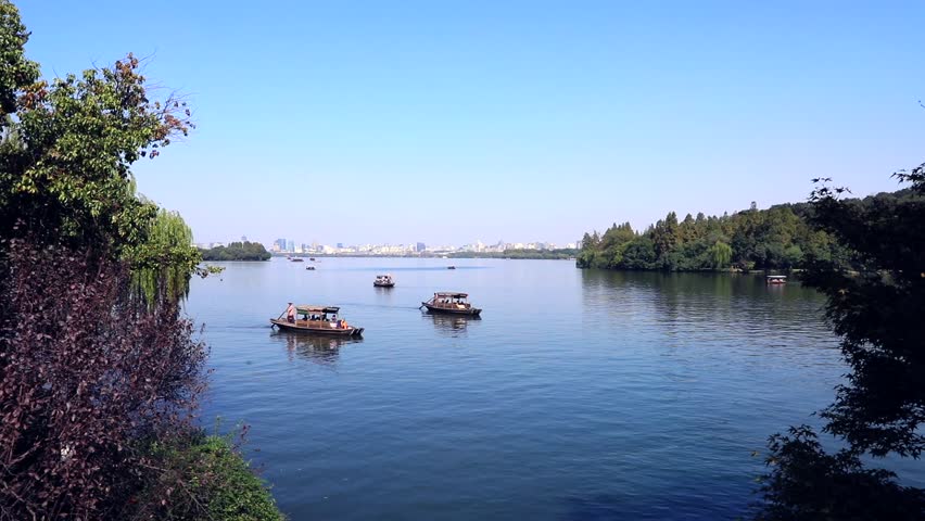 A small Chinese fishing boat with a boatman goes to the West Lake coast. Famous park in Hangzhou city center, China 