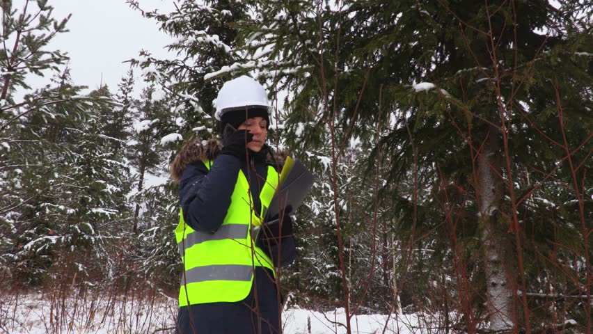 Female forestry worker using smart phone in woods